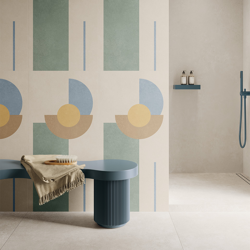 Badkamer met crèmekleurige wandtegels met een grafisch dessin in pastel, een blauwe wastafelbank en een vloer in grootformaat
