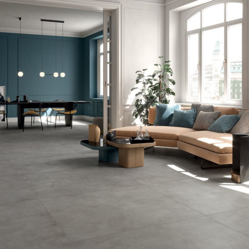 Lichte woonkamer met grootformaat betonlooktegels, een petrolblauwe wand en een ronde bank