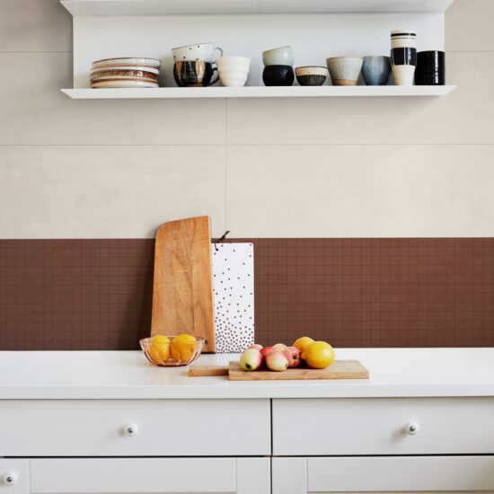 Keukenwand met een cremekleurige grootformaat tegel en daaronder een terracotta mozaïekband