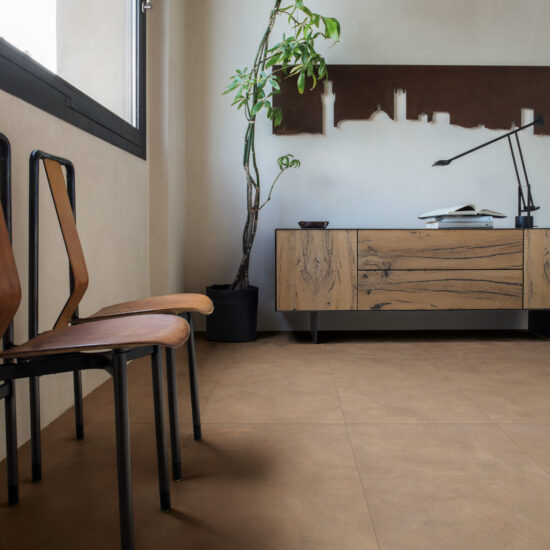 Ruimte met een warm bruine betonlookvloer, een houten dressoir, een plant en twee stoelen