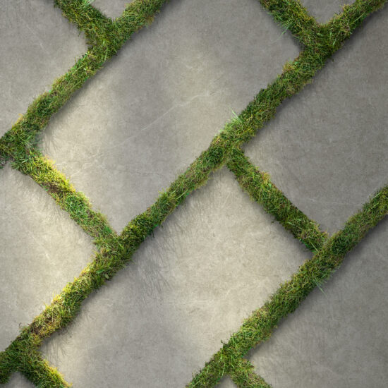 Grijze betonlooktegels diagonaal in een terras gelegd, met gras tussen de voegen